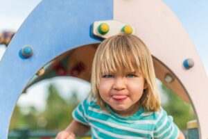 naughty little boy sticking his tongue out in the playground