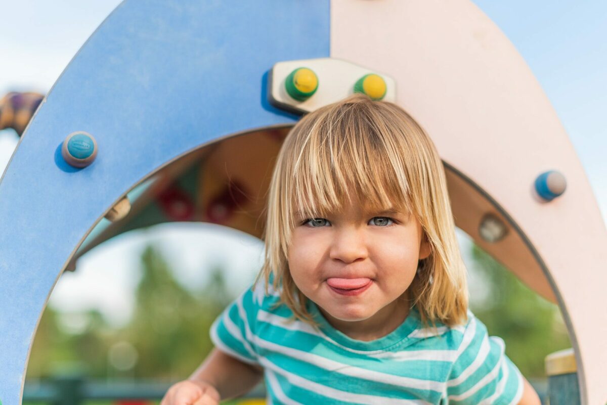 naughty little boy sticking his tongue out in the playground