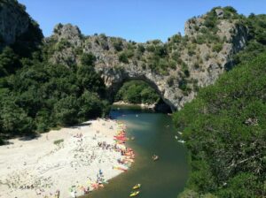 Pont d'Arc rock archway with canoes and tourists sunbathing
