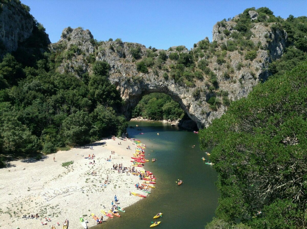 Pont d'Arc rock archway with canoes and tourists sunbathing