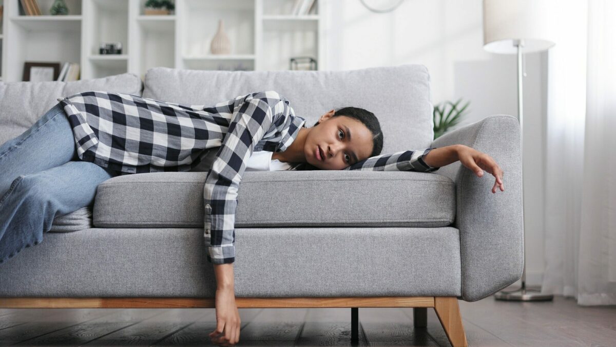 Tired african american girl lying on sofa feeling lethargic. Fee