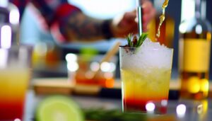 Un cocktail coloré et rafraîchissant sur le comptoir de la cuisine, avec les ingrédients et les ustensiles utilisés pour sa préparation en arrière-plan.